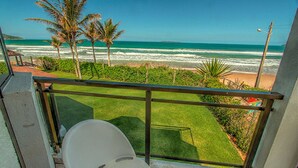 A balcony with a view of the beach, palm trees, and a clear sky. - Hotel Atlântico (Bombinhas)
