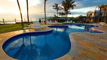 Una piscina al aire libre, sombrillas, tumbonas