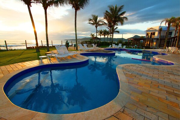 Una piscina al aire libre, sombrillas, sillones reclinables de piscina