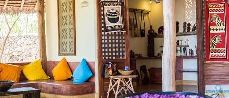 A cozy room with a wooden bench, colorful cushions, a woven basket, and a decorative wall hanging.