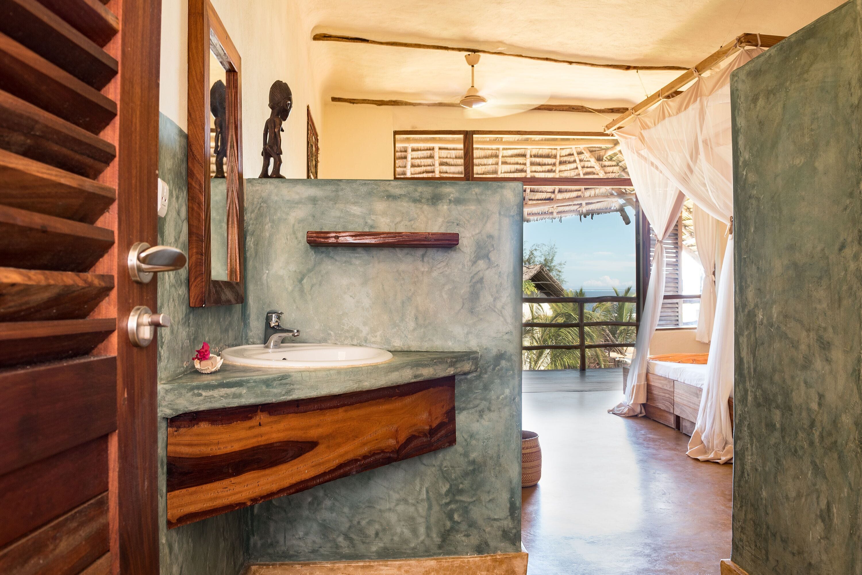 A bathroom with a marble sink, wooden vanity, and a view of the outdoors.