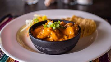 A bowl of curry with naan bread on a white plate.