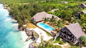 A resort with a swimming pool, thatched-roof buildings, and a beach. - Sunshine Marine Lodge (Matemwe)