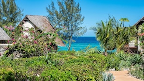 A tropical resort with thatched-roof cottages, lush greenery, and a view of the ocean. - Sunshine Marine Lodge (Matemwe)