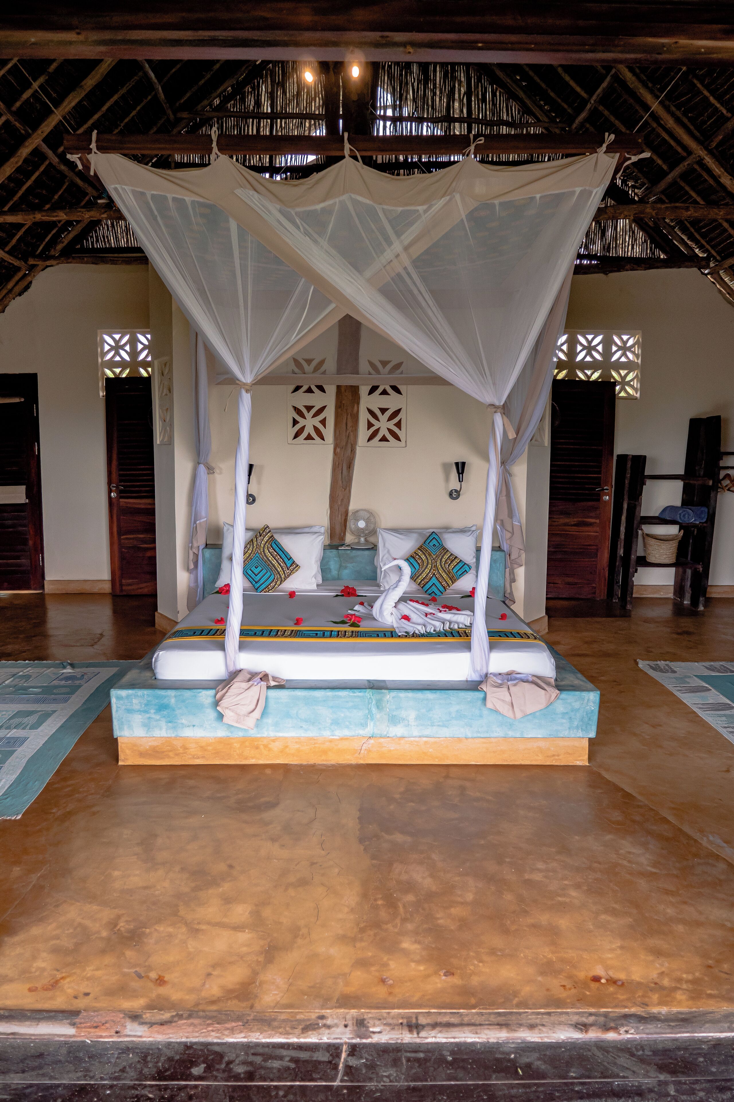 A bed with a canopy, a wooden floor, and a patterned wall.