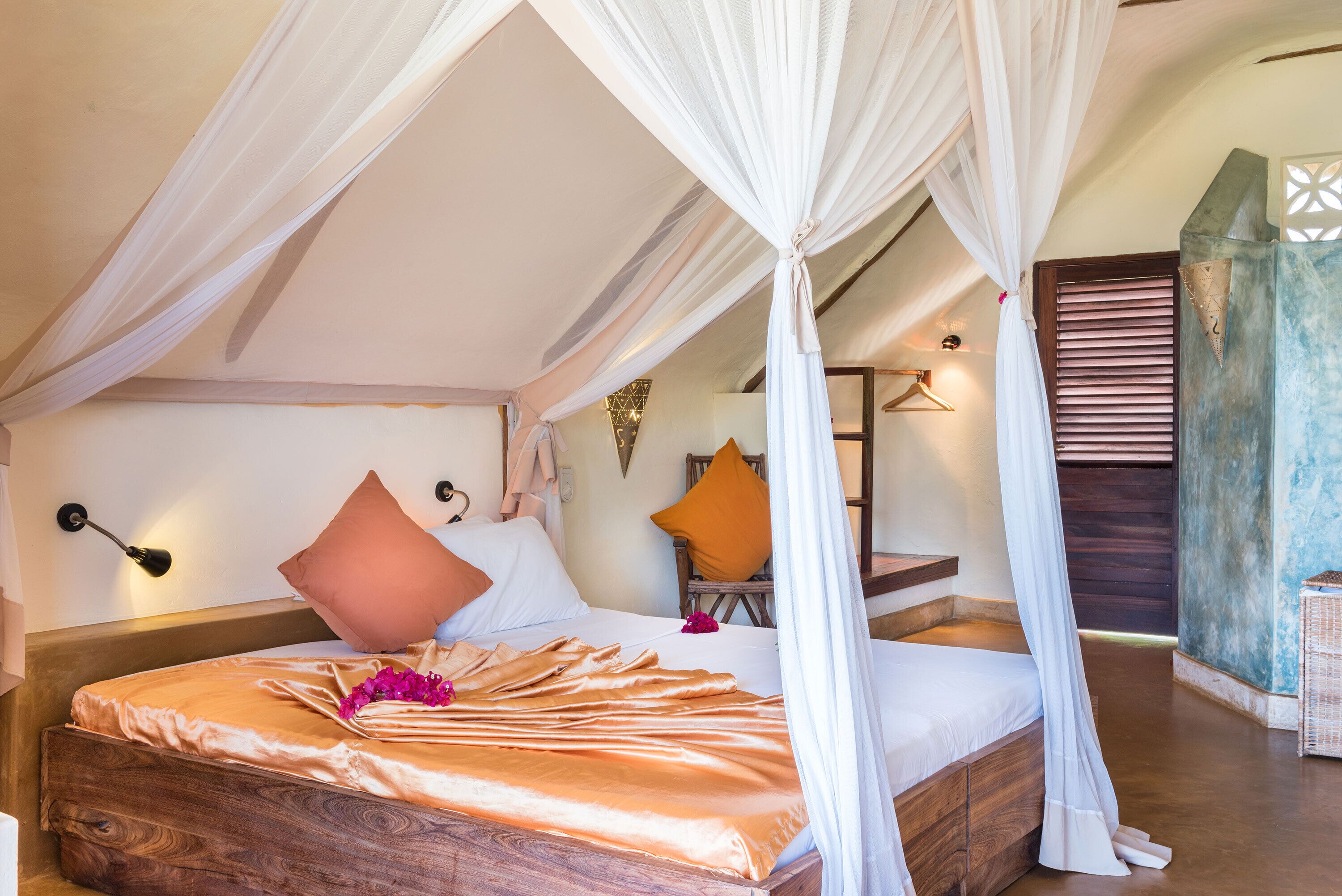 A four-poster canopy bed with a wooden headboard, a bedside table, and a nightstand.