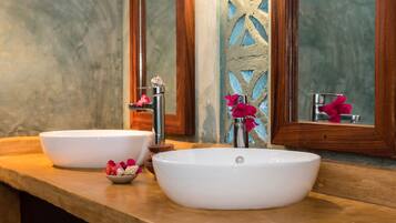 Un baño con dos lavamanos blancos, una encimera de madera y un espejo con un marco decorativo de madera.