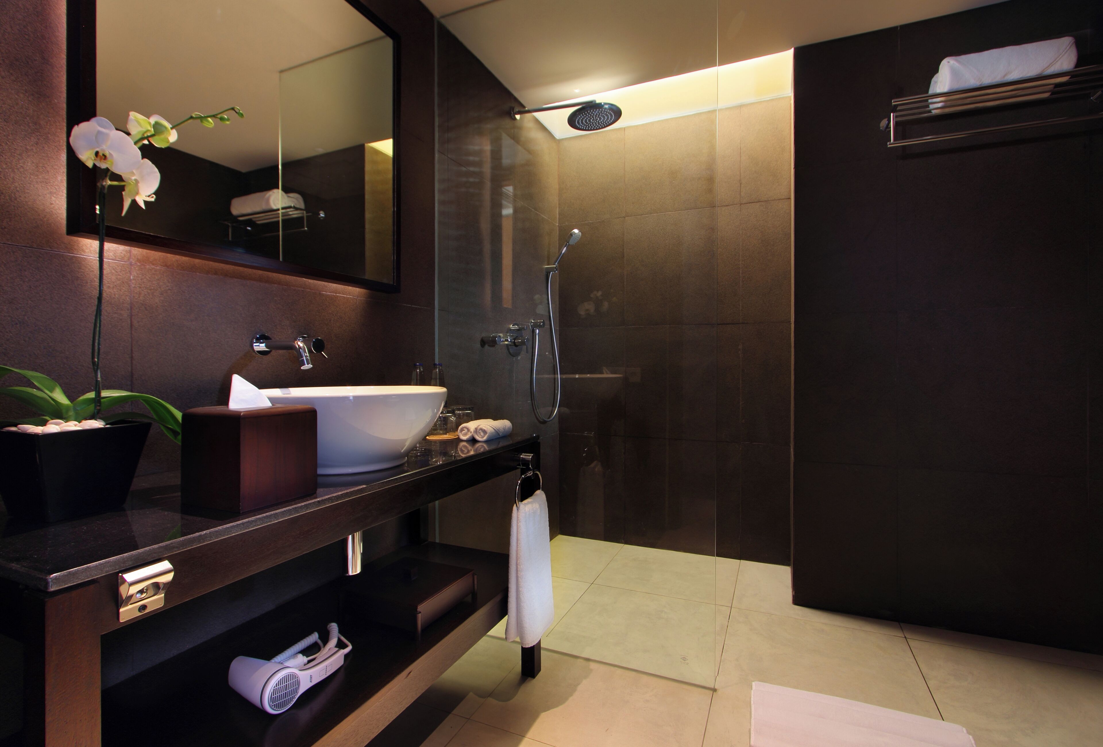 Un baño moderno con un espejo grande, un lavabo, un perchero para toallas y una zona de ducha.
