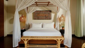 A bed with a canopy, a woven bench, and two wall-mounted lamps.
