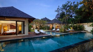 A modern resort with a swimming pool, sun loungers, and a well-lit bedroom area.