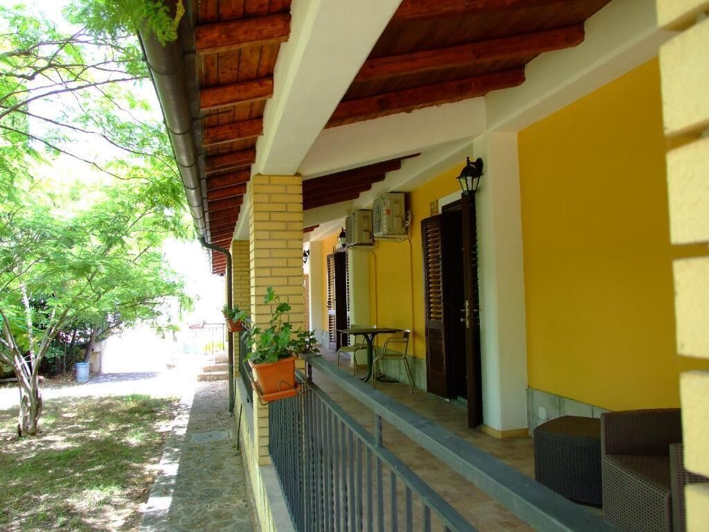 A covered outdoor area with a brick column, a railing, and potted plants.