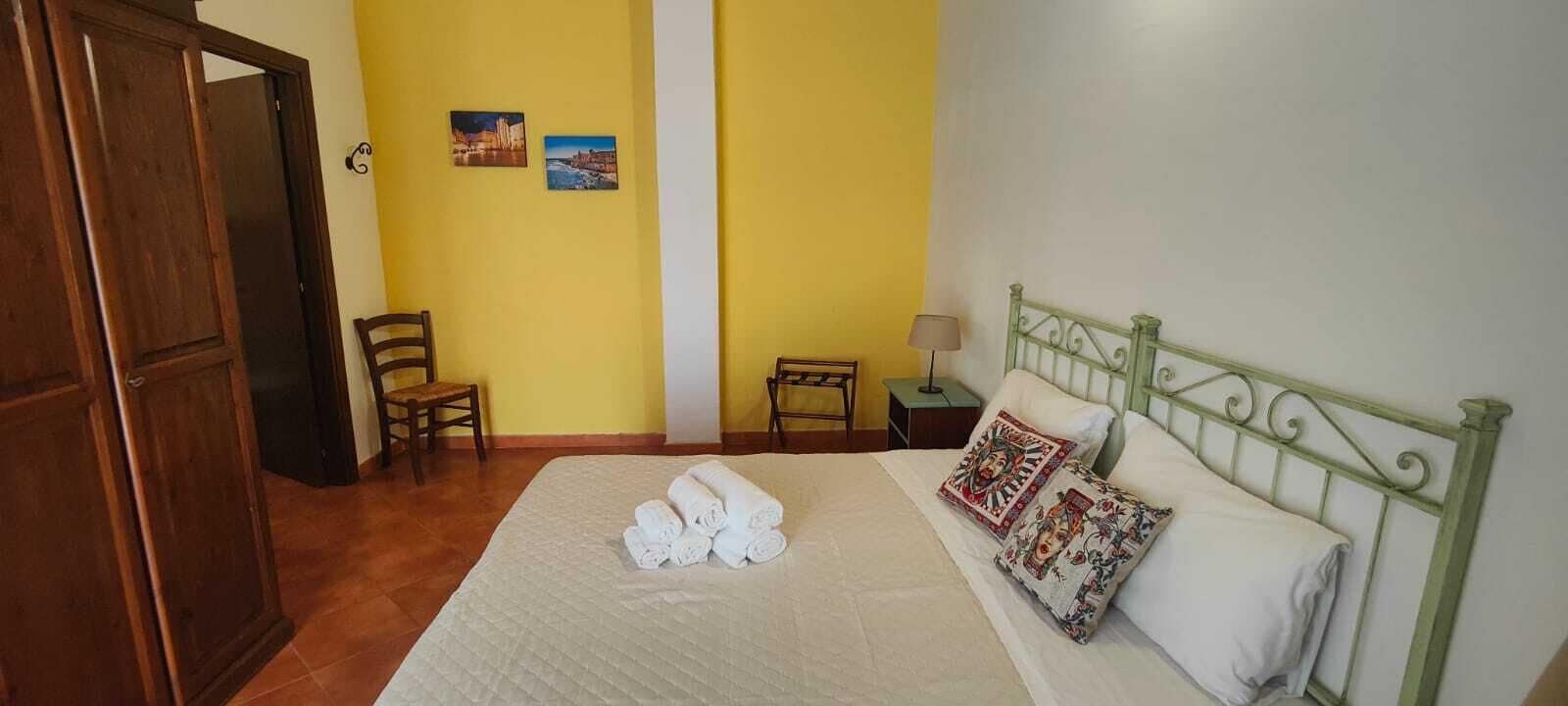 A bedroom with a bed, a chair, a nightstand, and a door.