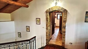 Una escalera conduce a una habitación con un arco de piedra, techo de madera y suelo de baldosas.