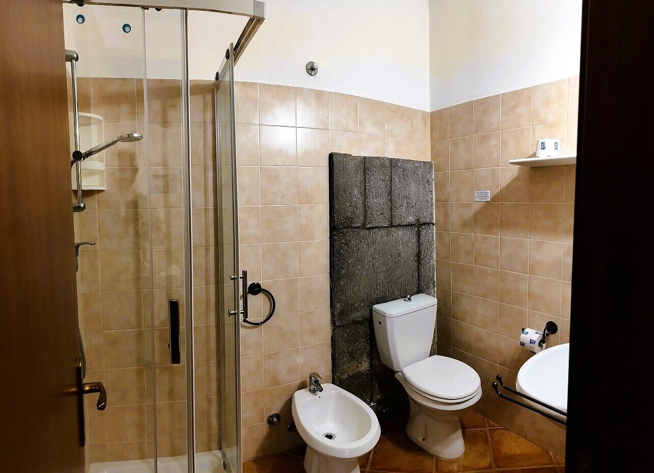 A bathroom with a glass shower enclosure, a bidet, a toilet, and a sink.