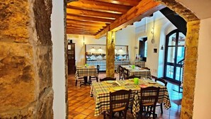 Un restaurante con manteles a cuadros, vigas de madera y paredes de piedra.
