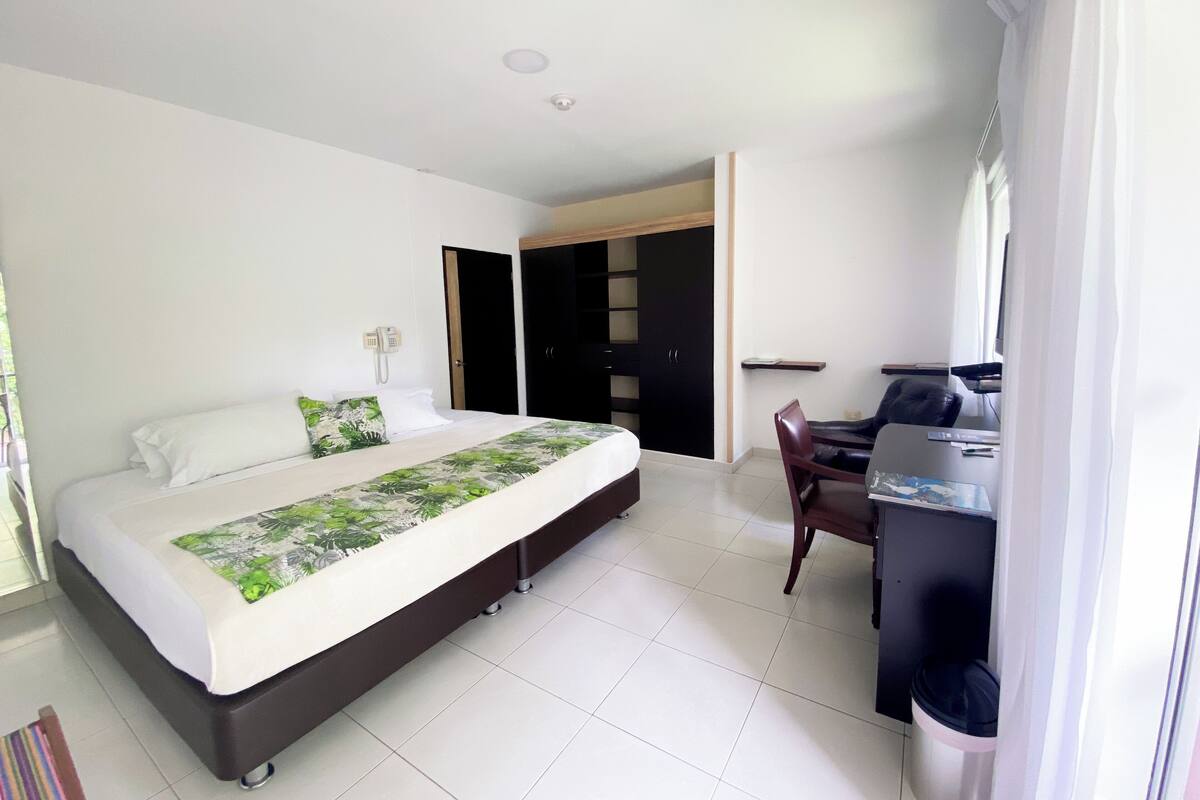 Une chambre d’hôtel comprenant un lit, un bureau avec une chaise, une armoire et un téléphone.