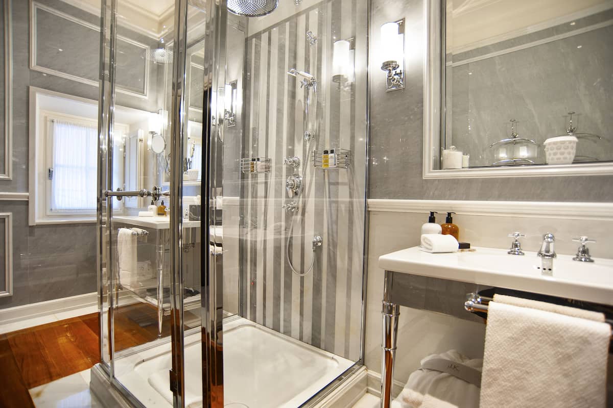 A modern bathroom with a glass-enclosed shower, a white sink, and a large mirror.