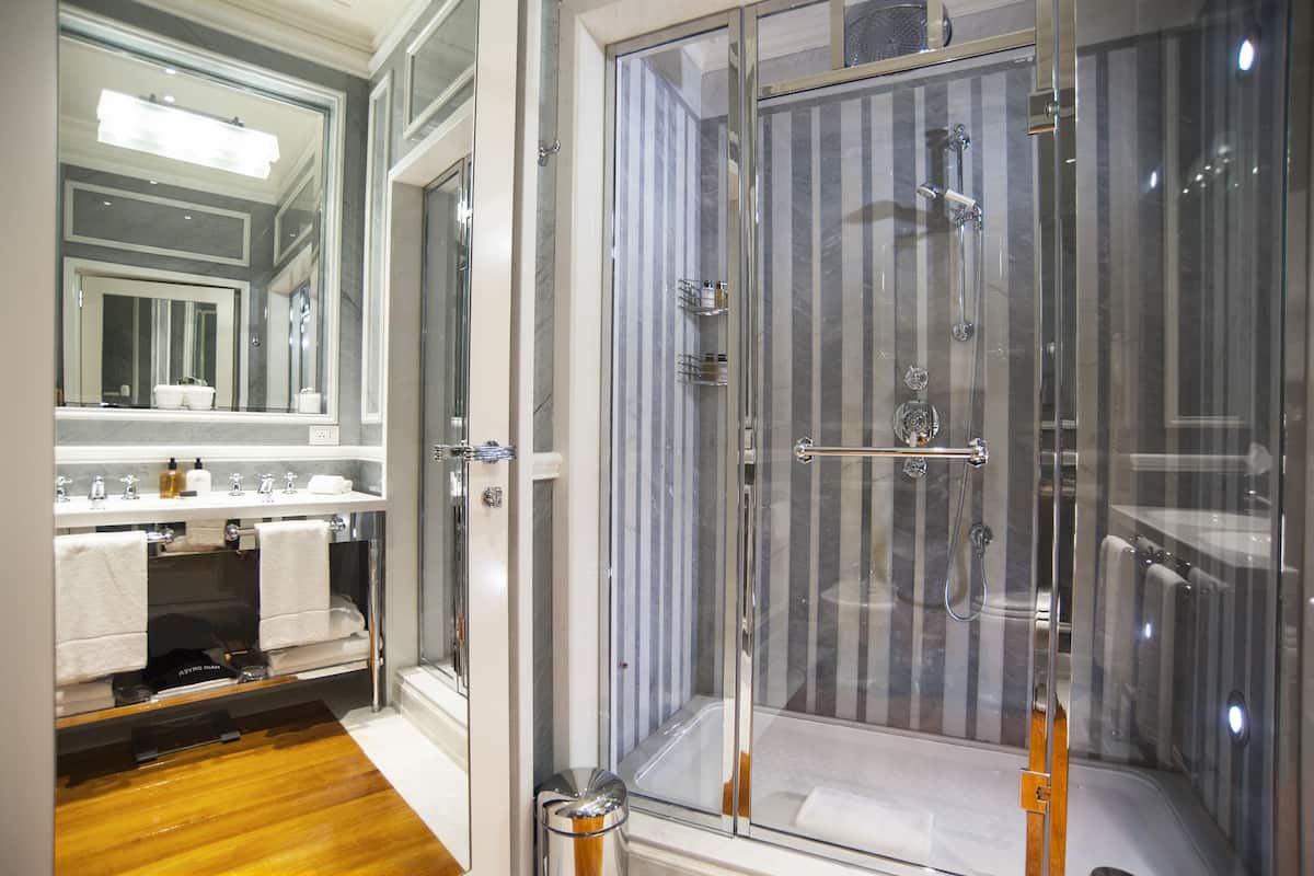 A modern bathroom with a glass-enclosed shower, a vanity with a mirror, and a wooden floor.