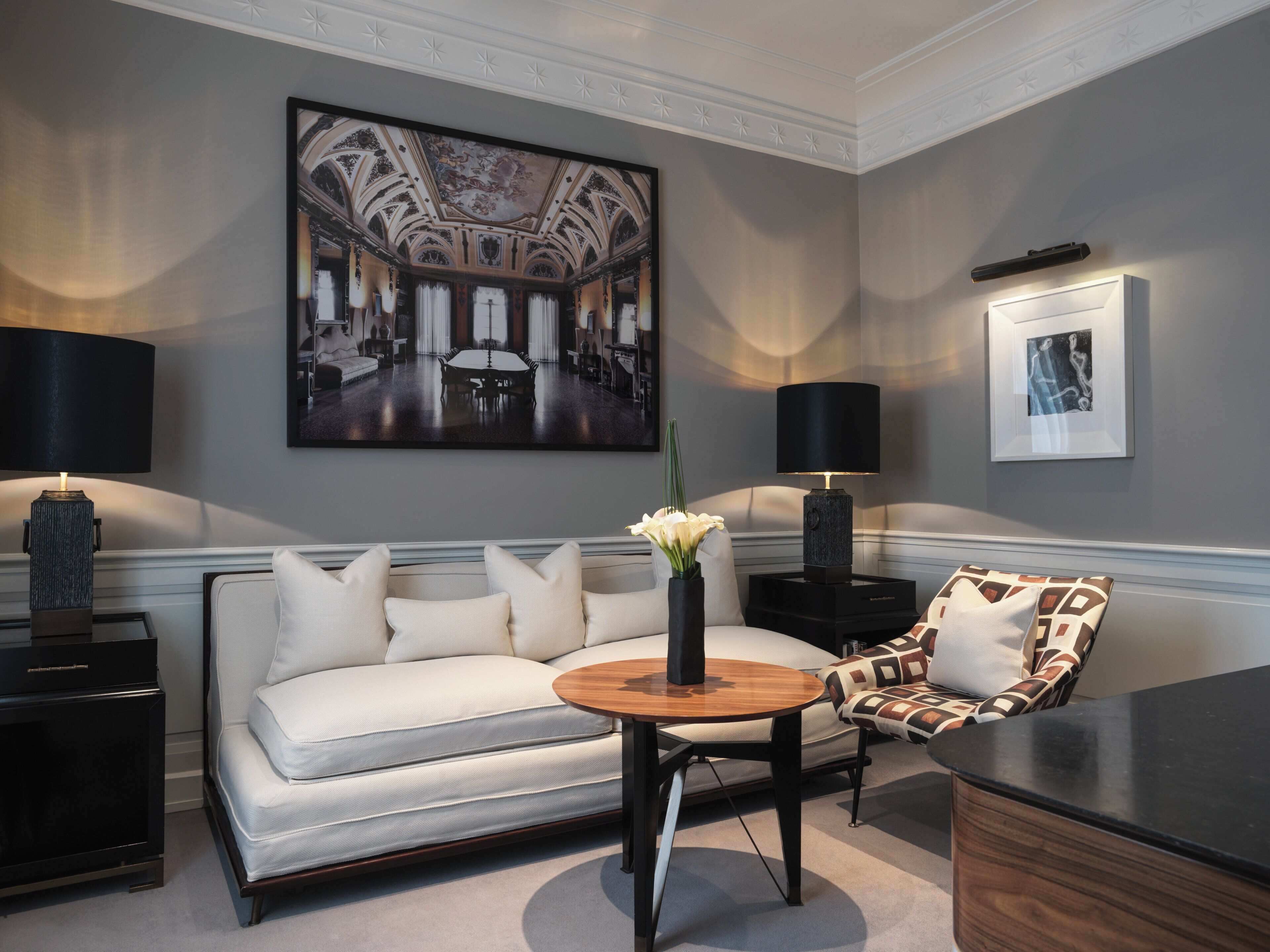 A modern living room with a sofa, armchair, coffee table, and lamps.
