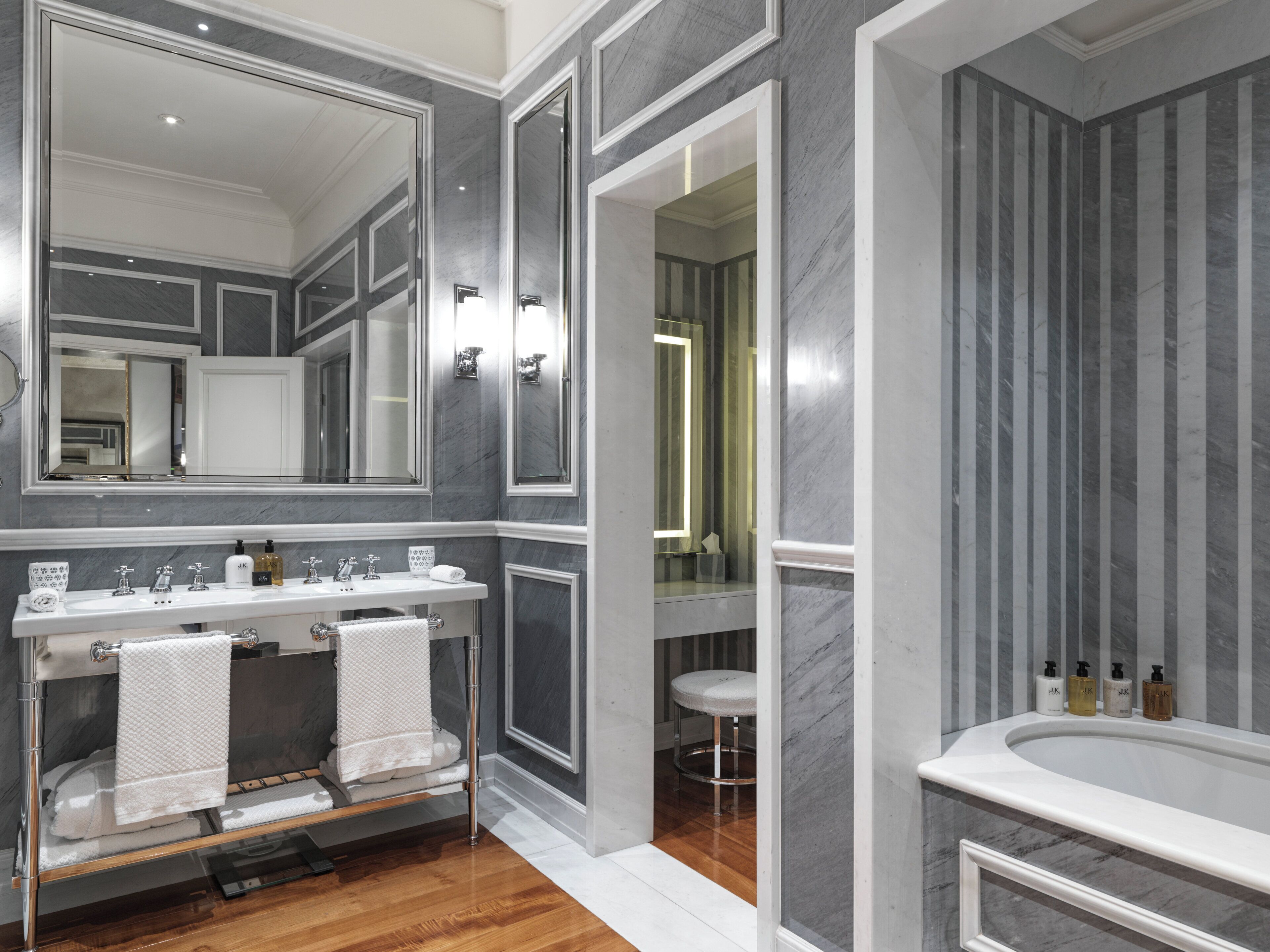 A modern bathroom with a large mirror, a vanity with a sink, and a bathtub.