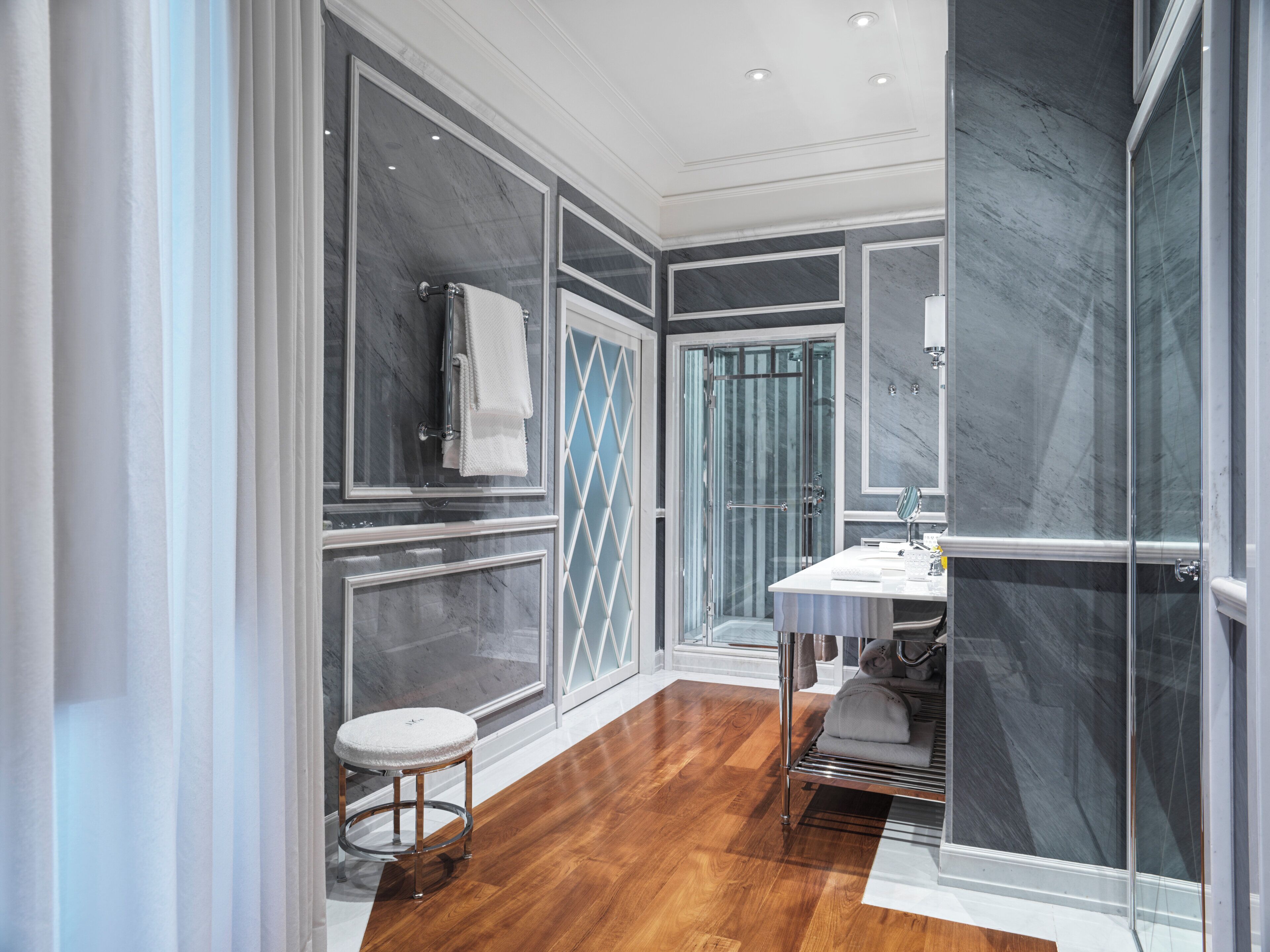 A modern bathroom with a glass shower, a vanity with a mirror, and a wooden floor.