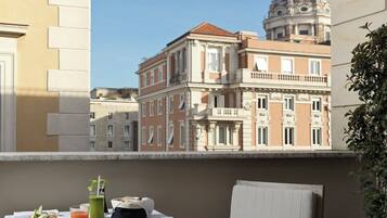 A balcony with a table set for breakfast, a chair, and a view of historic buildings.