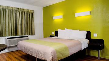 A hotel room with a bed, bedside tables, a heater, and a window with curtains.