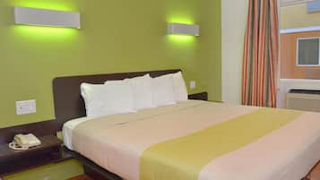 Una camera d'albergo con un letto, un telefono sul comodino e due lampade fissate alla parete.
