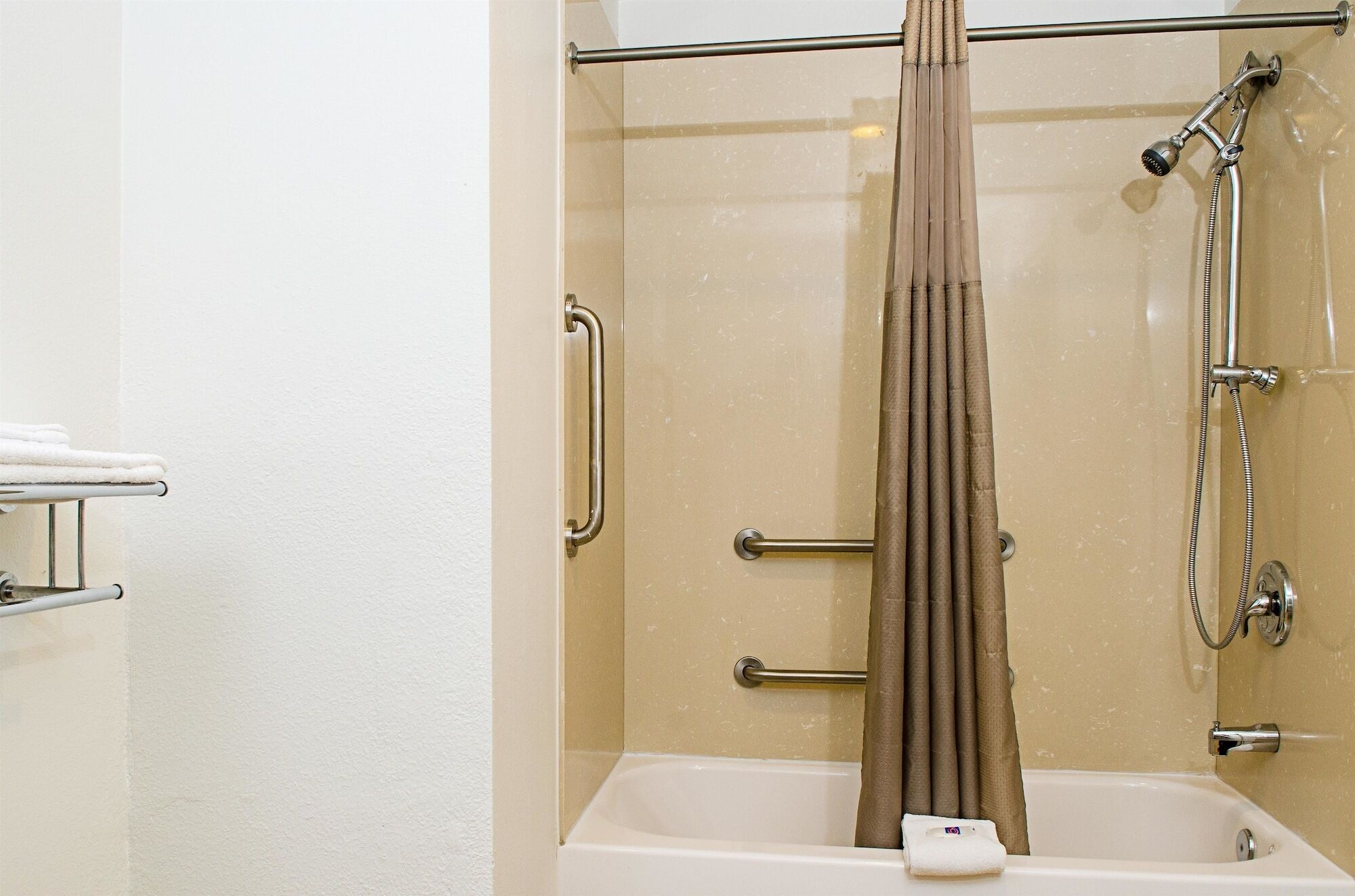 A shower with a glass door, a handheld showerhead, and a towel rack.