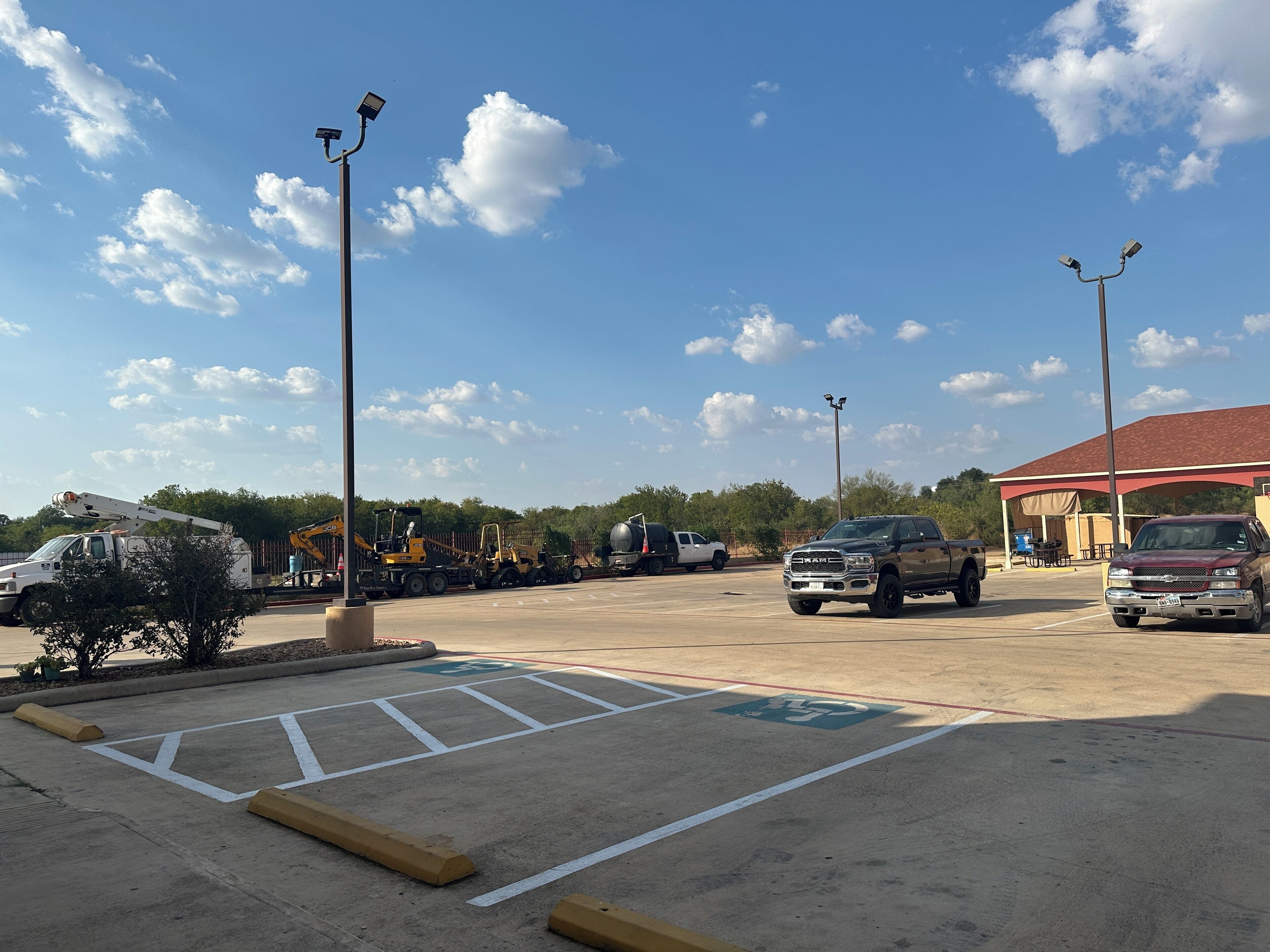 A parking lot with a covered area, marked handicapped spaces, and a red-roofed building.