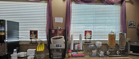 Una barra de desayuno con máquinas de café, dispensador de café y dispensadores de cereales.