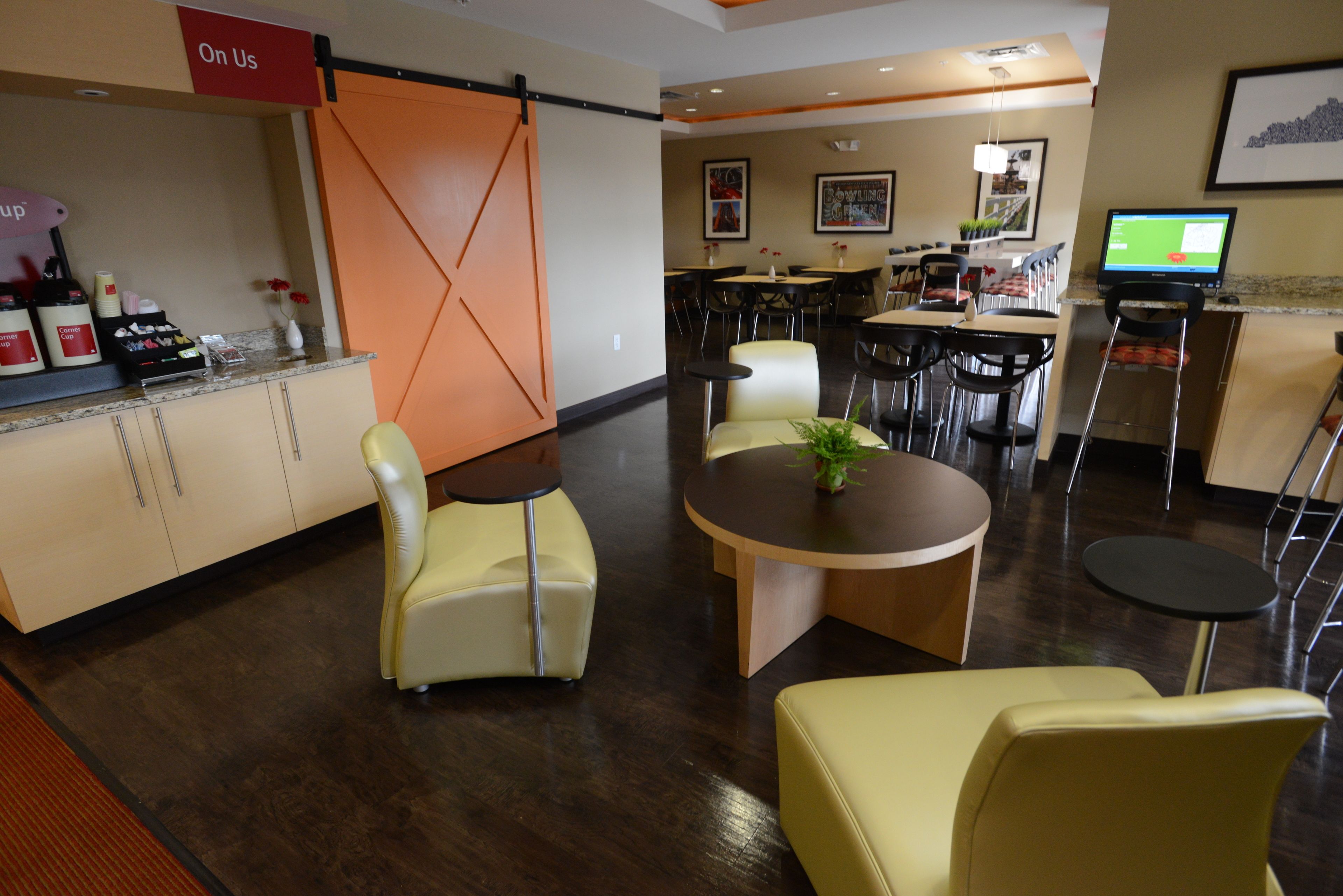 A modern hotel lobby with a reception desk, seating area, and dining space.