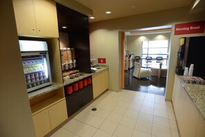 Un espace pour le petit-déjeuner équipé d’un réfrigérateur, d’une machine à café et de sièges.