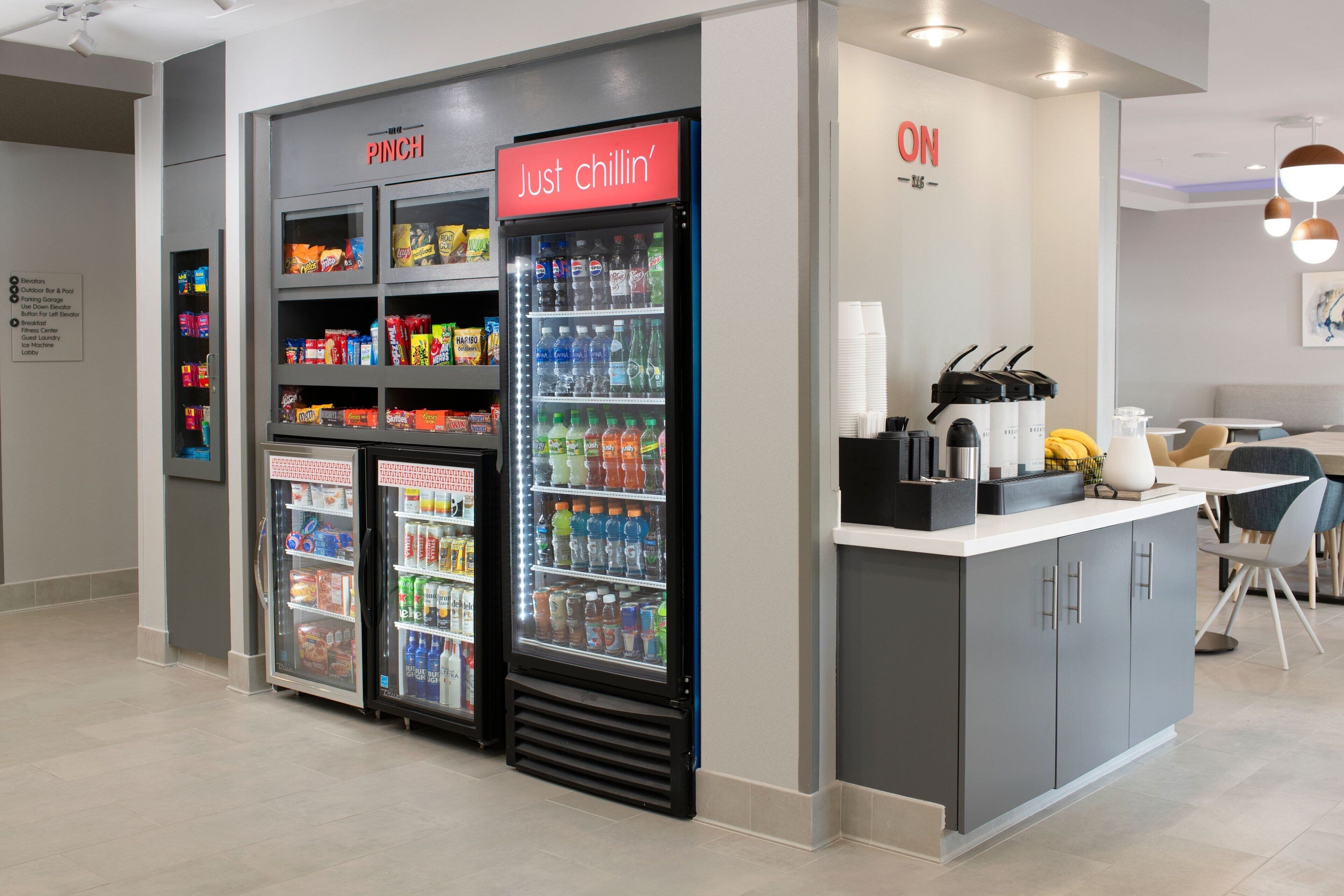 A modern kitchenette with a refrigerator, a coffee machine, and a microwave.