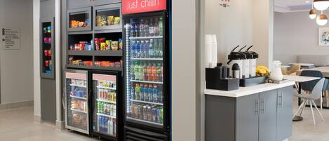 A modern kitchenette with a refrigerator, a coffee machine, and a microwave.