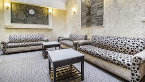 Un área de descanso con sofás estampados, una mesa de centro y un reloj de pared.