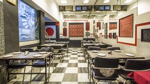 Un salón de conferencias con piso a cuadros, sillas negras y mesas dispuestas para reuniones.