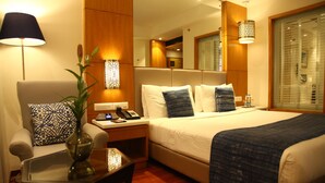 Ein Hotelzimmer mit Bett, Nachttisch, Lampe, Stuhl und Spiegel.