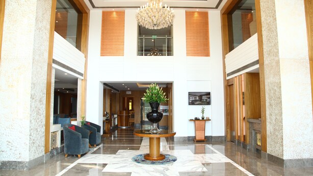 Eine Lobby mit Marmorboden, einem zentralen Tisch mit Blumenvase und einem Chandelier.