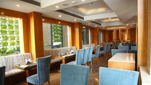Ein Restaurant mit Holzboden, blau gepolsterten Stühlen und einem langen Esstisch.