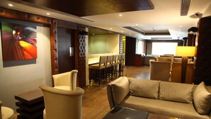 Eine moderne Hotelhalle mit einer Couch, Sesseln, einem Essbereich und einem Gemälde an der Wand.