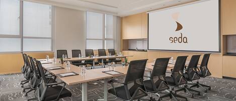 A conference room with a large screen displaying the logo "soda", a long table with chairs, and large windows.