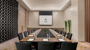 A conference room with a long table, black chairs, and a projector screen displaying the logo "seda BCC".