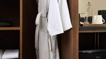 A wooden wardrobe with a hanging robe and a black appliance, likely a coffee maker, on the counter.