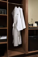 A wooden wardrobe with a hanging robe and a black appliance, likely a coffee maker, on the counter.