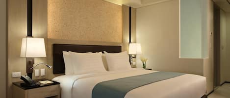 Habitación de hotel con cama, lámparas de noche, escritorio y teléfono.