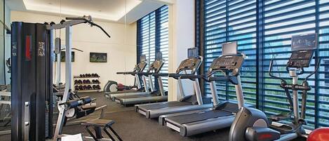 Une salle de sport équipée de tapis de course, de vélos elliptiques et de matériel de musculation.