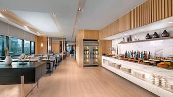 A modern hotel lobby with a long reception desk, seating area, and a bar with a marble countertop.