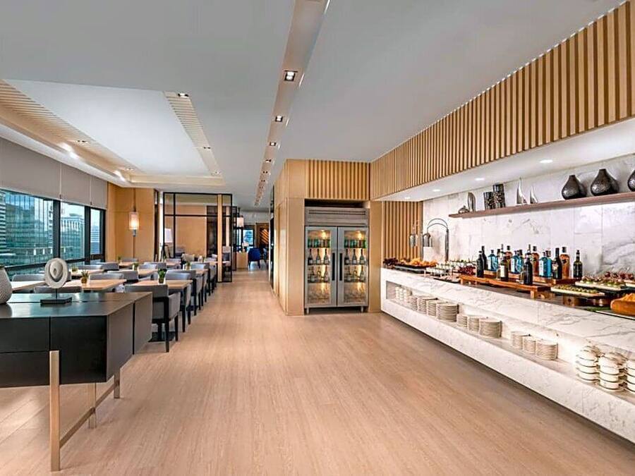 A modern hotel lobby with a long reception desk, seating area, and a bar with a marble countertop.
