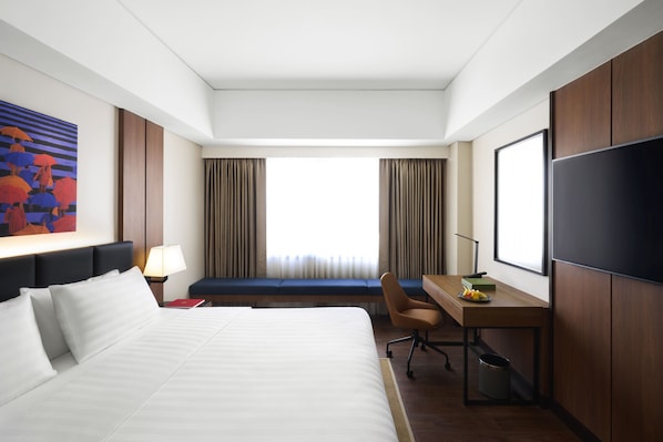 A hotel room with a large bed, a desk with a chair, a television, and a window with curtains. - Seda Bonifacio Global City Manila (Taguig)